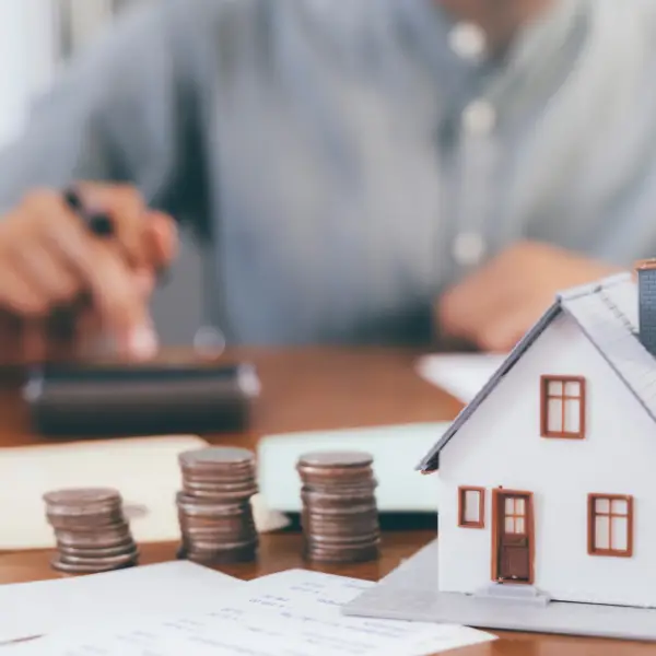 Monety obok modelu domu symbol kredytu hipotecznego